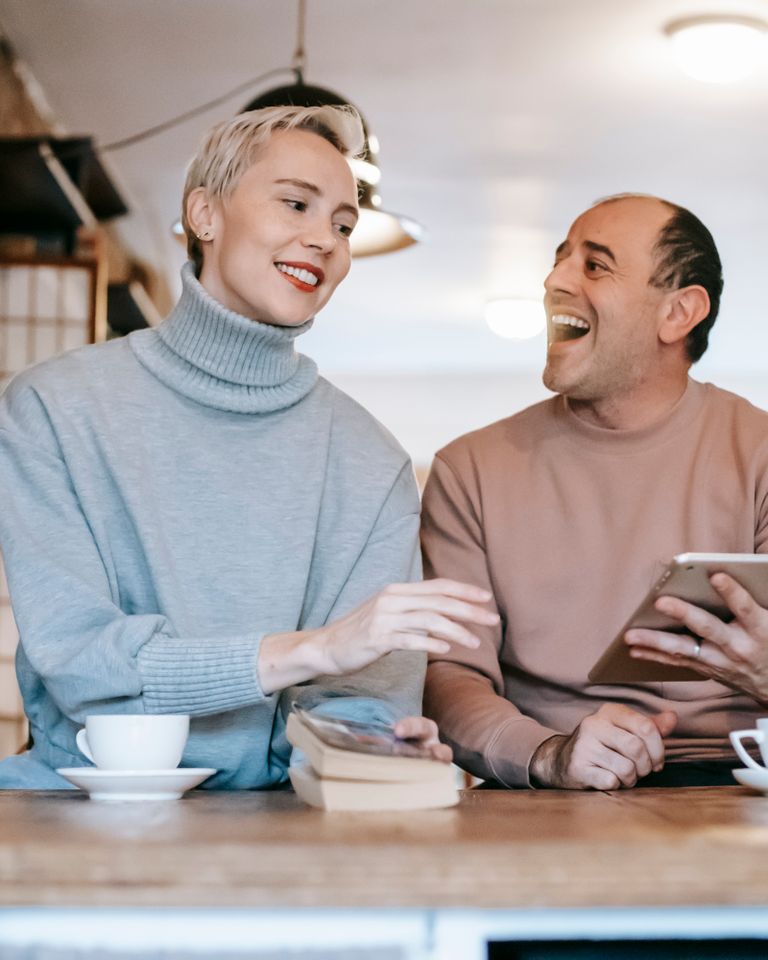 Two partners laughing over coffee at a kitchen counter